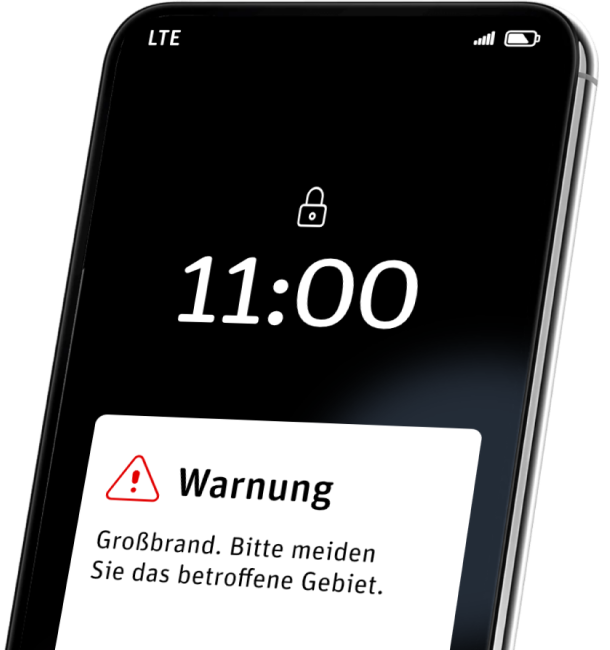 Ein Smartphone zeigt eine Warnmeldung: Großbrand. Bitte meiden Sie das betroffene Gebiet.